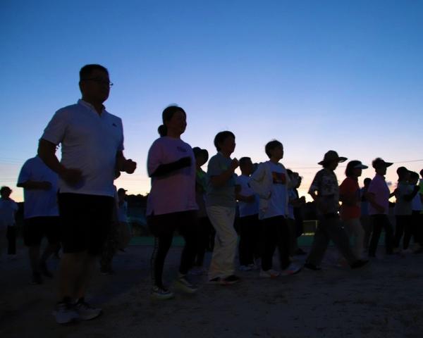 夕焼けを背中にウォーキングする講座参加者