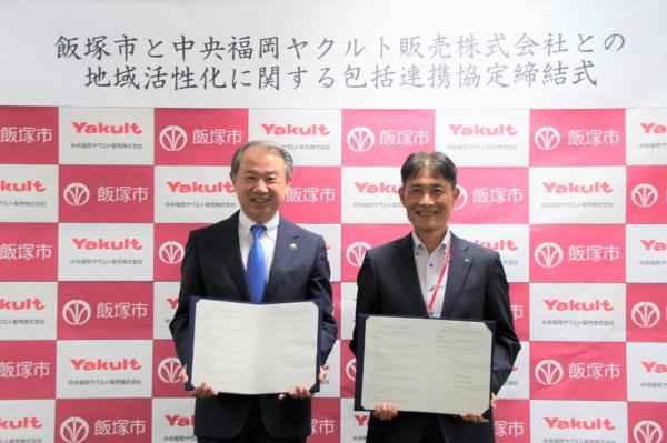 締結書を手に微笑む武井市長と中央福岡ヤクルト販売㈱の小島社長
