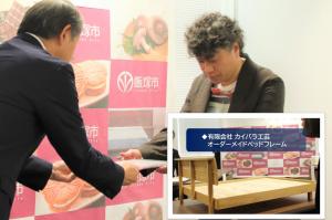 オーダーメイドベッドフレーム （有限会社 カイバラ工芸）で認定を受けた代表の貝原輝邦氏に認定証を渡す武井市長