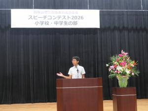ステージ上で身振り手振りを交えながら英語のスピーチを行う中学生
